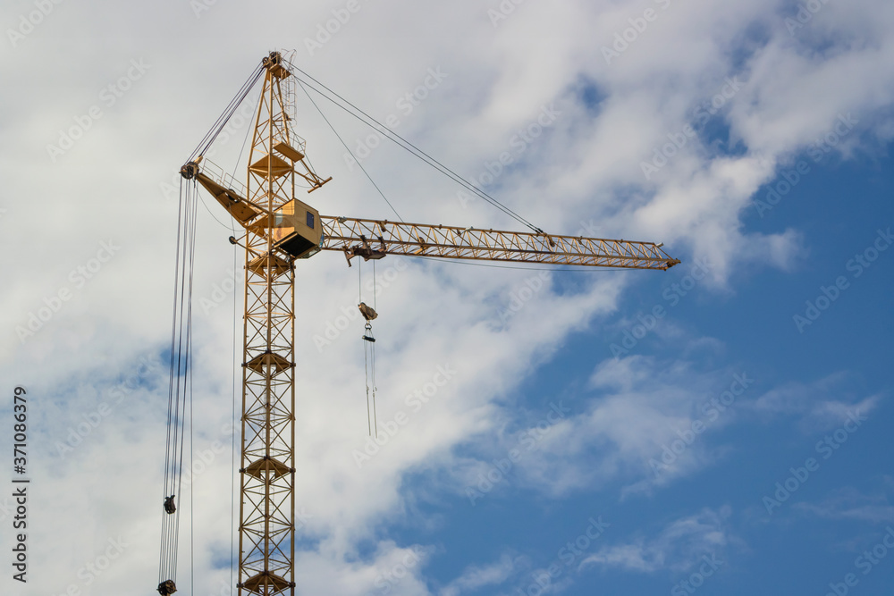 Single tower crane with boom against a cloudy sky
