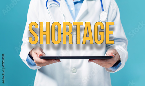 Canvas Print Covid-19 Shortage theme with a doctor using a tablet computer