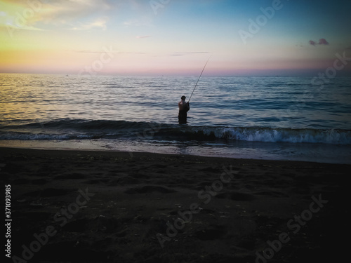 Sunset Shine Beach Horizon View With Man Fishing In The Evening At The Village, Seririt, North Bali, Indonesia