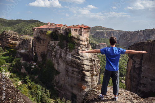 Obraz na płótnie Western man opening arms facing dramatic landscape of Meteora monasteries built on vertical rock formations in Greece w salonie