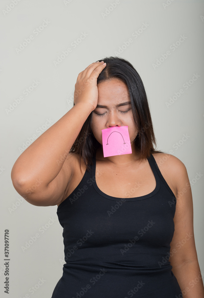 Portrait of young overweight Asian woman against white background Portrait of young overweight Asian woman against white background
