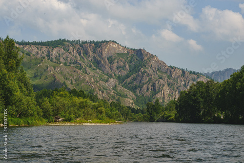 White Iyus river among hills and rock massifs. People float down the river on catamarans. Russia, Khakassia.