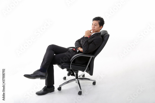 South east Asian young Chinese man wearing formal business office ware on white background sitting on office chair relax think success happy worried