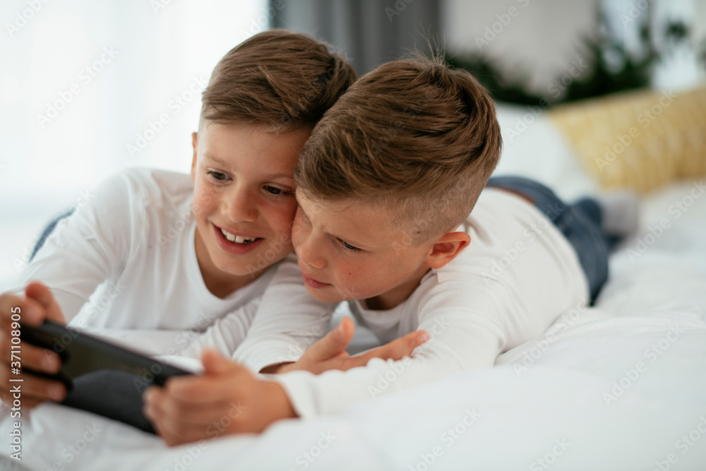 Two little brothers are playing games on the phone. Beautiful boys enjoying at home... Two little brothers are playing games on the phone. Beautiful boys enjoying at home...
