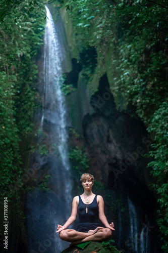 Yoga practice and meditation in nature. Woman practice near waterfall.