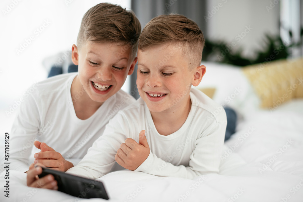 Two little brothers are playing games on the phone. Beautiful boys enjoying at home... Two little brothers are playing games on the phone. Beautiful boys enjoying at home...