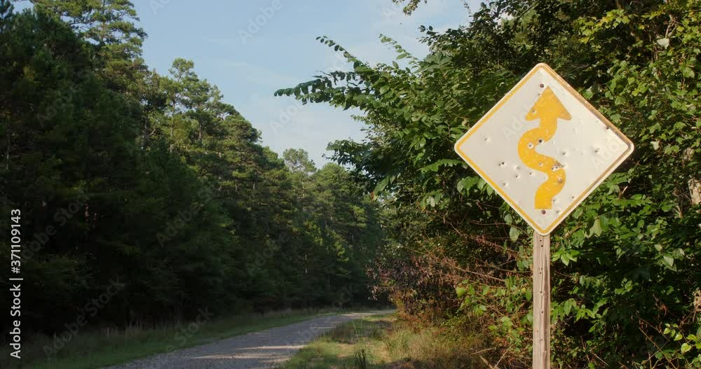 A wide shot of a road warning sign that has been vandalized by multiple