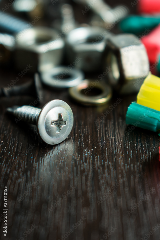 Hardware store tools like a drill and some bolts on a black wooden table Hardware store tools like a drill and some bolts on a black wooden table