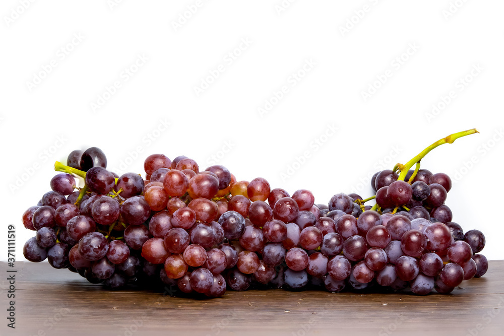 Close-up of red seedless grapes with water droplets on a wooden table and white background. Close-up of red seedless grapes with water droplets on a wooden table and white background.