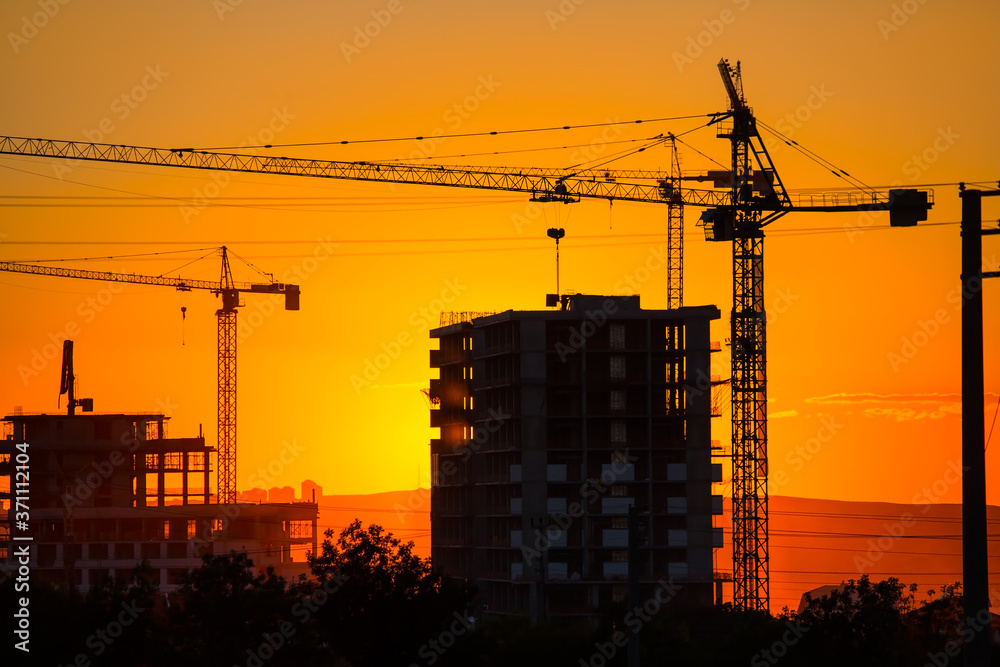 Construction crane and skyscraper at sunset