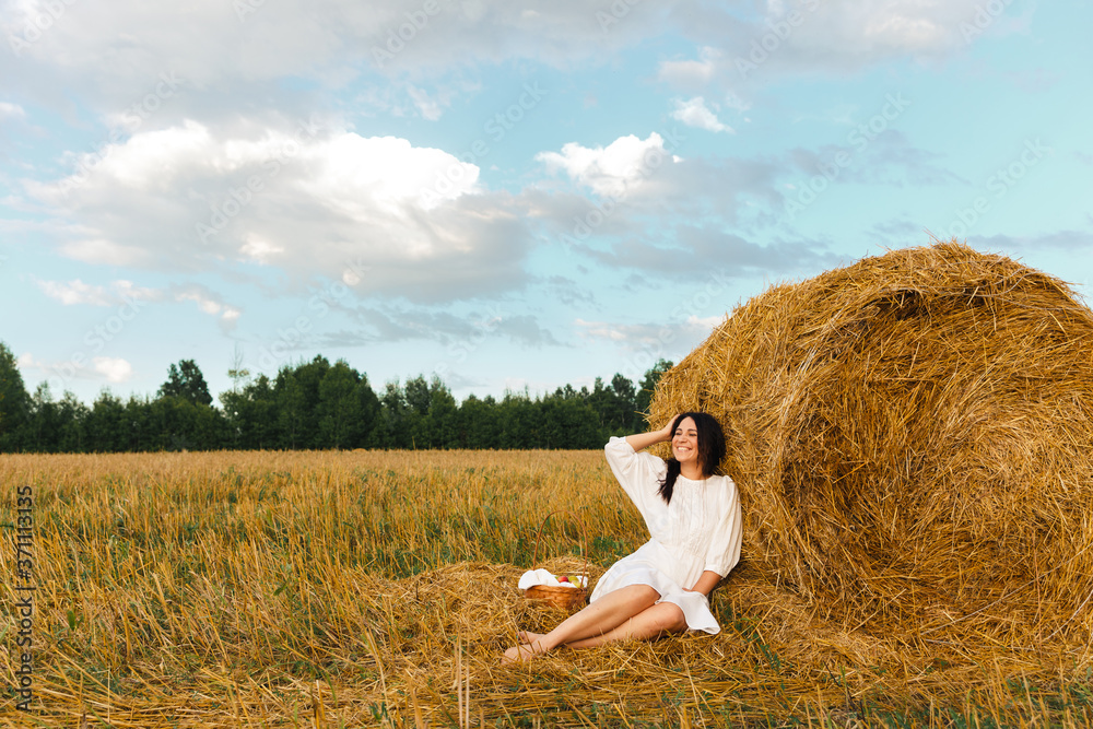 Romantic young women outdoor near the hayloft with basket with apples and pears. Harvesting in village in sumer or autumn. Healthy food. Photo session at sunset Romantic young women outdoor near the hayloft with basket with apples and pears. Harvesting in village in sumer or autumn. Healthy food. Photo session at sunset