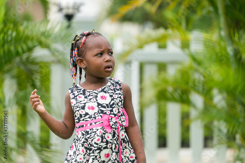 portrait of cute young african girl playing in outdoor garden.