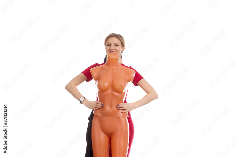 A young woman in a red dress, stands behind a demonstration mannequin A young woman in a red dress, stands behind a demonstration mannequin