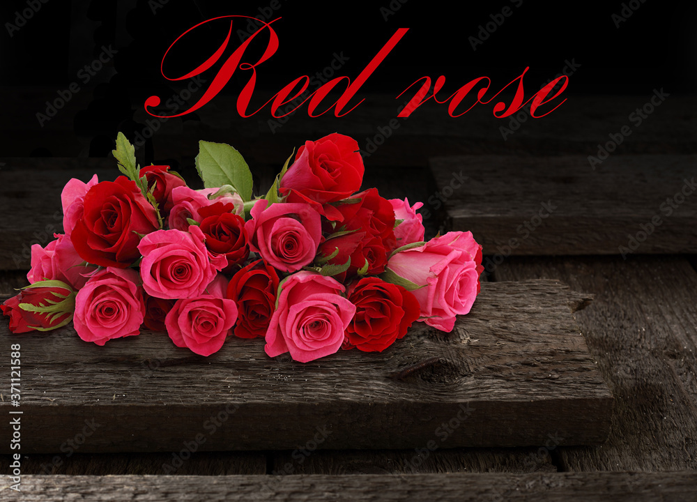 Bouquet of red roses on the boards. Bright and catchy flowers on a black background.