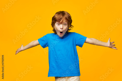 Red-haired boy holding hands in different directions surprise emotions blue t-shirt childhood Copy Space