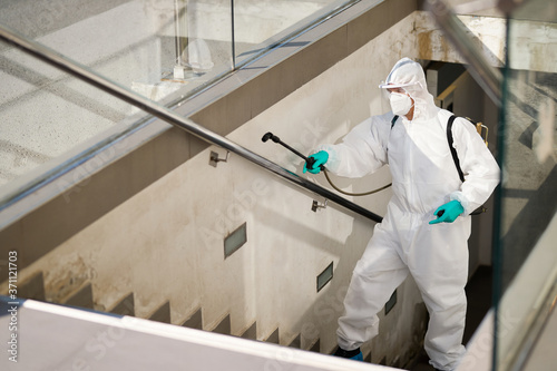 Φωτογραφία Sanitation worker in hazmat suit disinfecting public passages during COVID-19 pandemic
