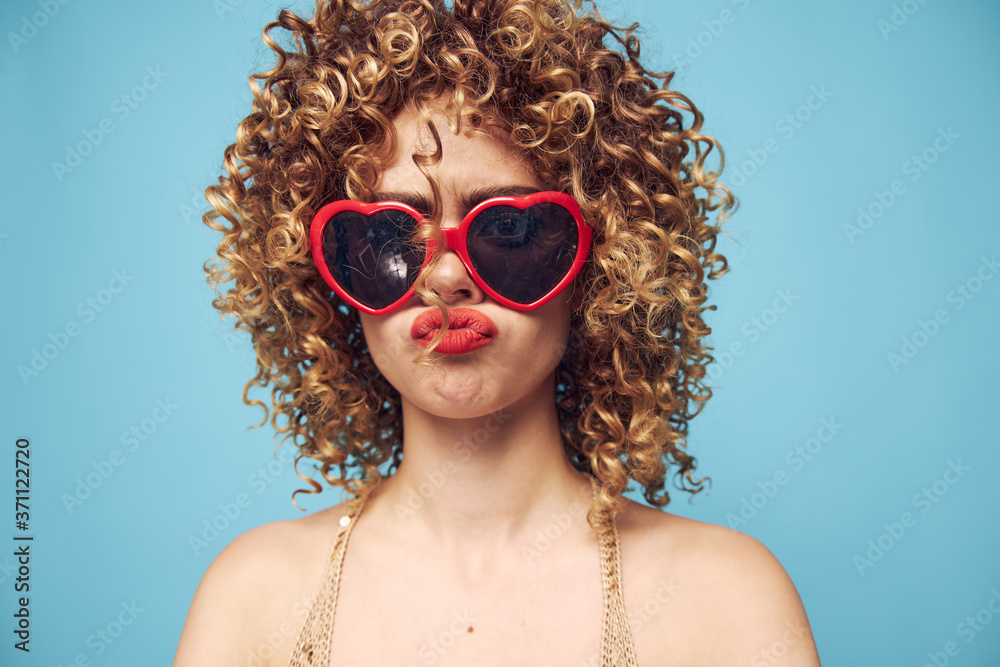 Enthusiastic girl party on a blue background, red sunglasses Enthusiastic girl party on a blue background, red sunglasses