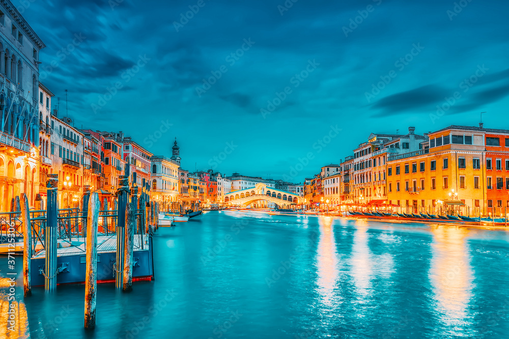 Naklejka premium Rialto Bridge (Ponte di Rialto) or Bridge of Sighs and view of the most beautiful canal of Venice - Grand Canal and boats, gondolas, mansions along. Night view. Italy.