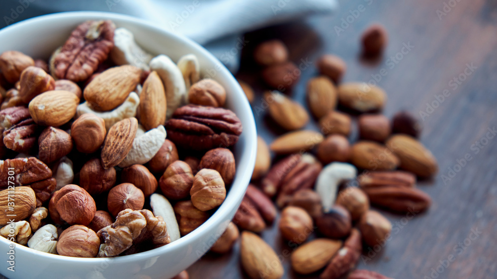 Wooden bowl with mixed nuts on table top view. Healthy food and snack. Walnut, pistachios, almonds, hazelnuts and cashews. Wooden bowl with mixed nuts on table top view. Healthy food and snack. Walnut, pistachios, almonds, hazelnuts and cashews.