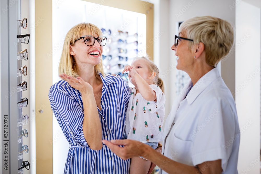 Fototapeta premium Mother and daughter in optician shop buying eyeglasses