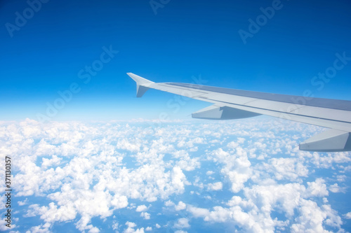 Airplane flying above the summer clouds, aerial wing view.