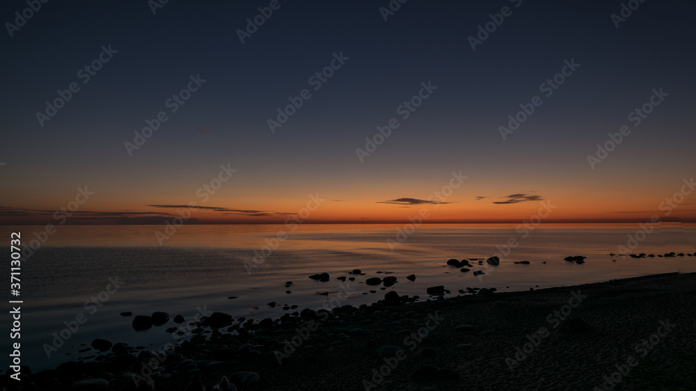 orange sunset by the sea, black stone silhouettes against the sea background, summer orange sunset by the sea, black stone silhouettes against the sea background, summer