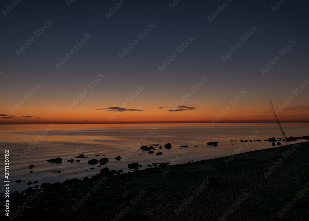orange sunset by the sea, black stone silhouettes against the sea background, summer orange sunset by the sea, black stone silhouettes against the sea background, summer