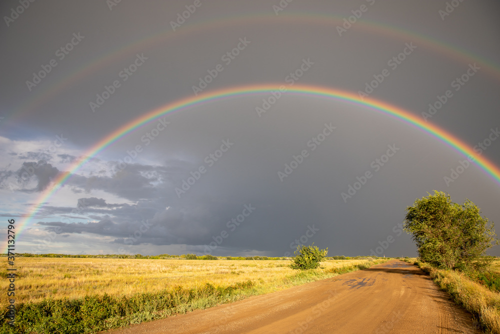 Naklejka premium Cumulonimbus clouds, torrential rain and double rainbow over the steppe road. Akmola Region, Kazakhstan.
