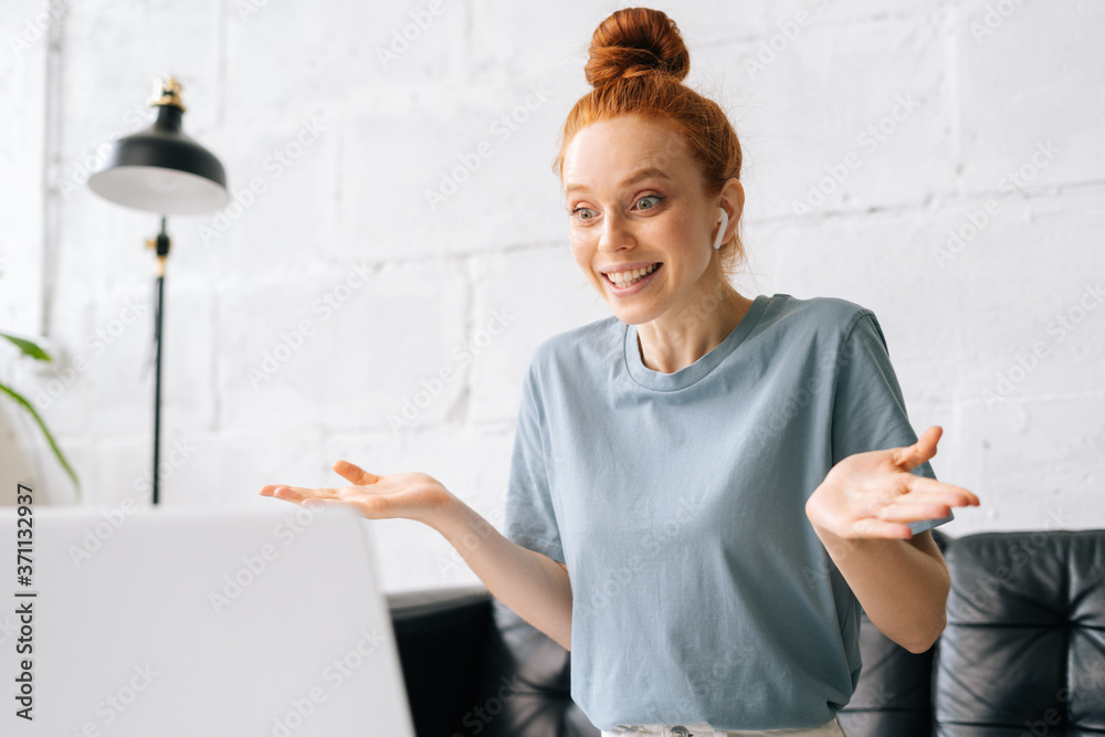 Happy surprised redhead young woman is looking at laptop screen with amazed expression, talking on video call, online communication. Attractive girl speaking on video call with friend client colleague Happy surprised redhead young woman is looking at laptop screen with amazed expression, talking on video call, online communication. Attractive girl speaking on video call with friend client colleague