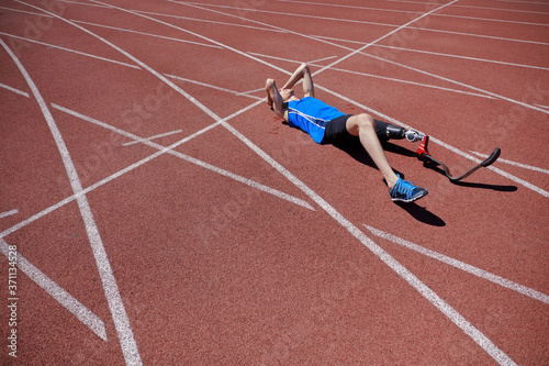 Adaptive sportsman laying on the running track outdoor after failure