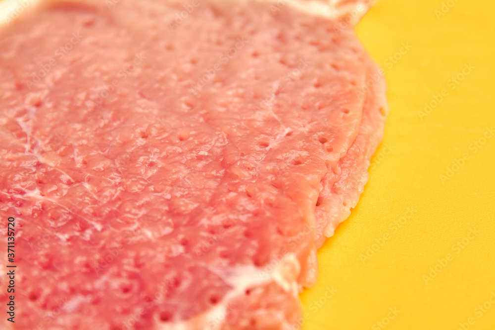 A piece of pork on cutting board after tenderizing is prepared for cooking A piece of pork on cutting board after tenderizing is prepared for cooking