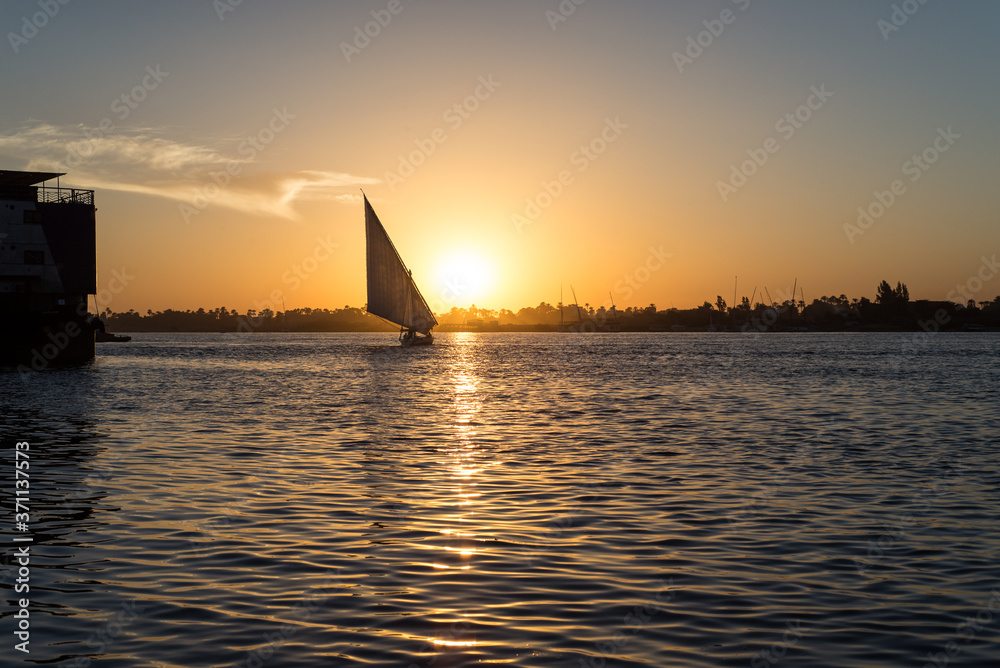 A felucca traditional wooden sailing boat used in Egypt sailing in Nile river during sunset