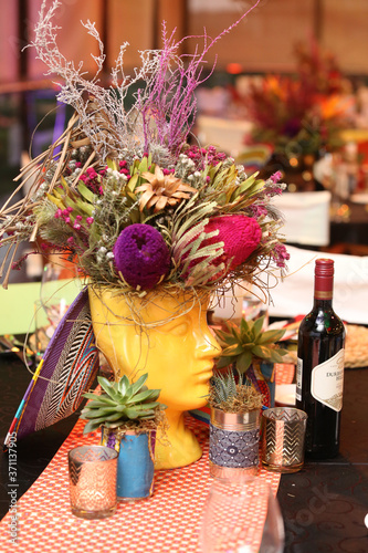 Bunch of colorful flowers in a yellow face shaped vase.