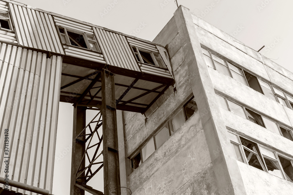 Obraz premium Old, abandoned concrete plant with iron rusty tanks and metal structures. The crisis, the fall of the economy, stop production capacity led to the collapse. Global catastrophe. Old photo effect