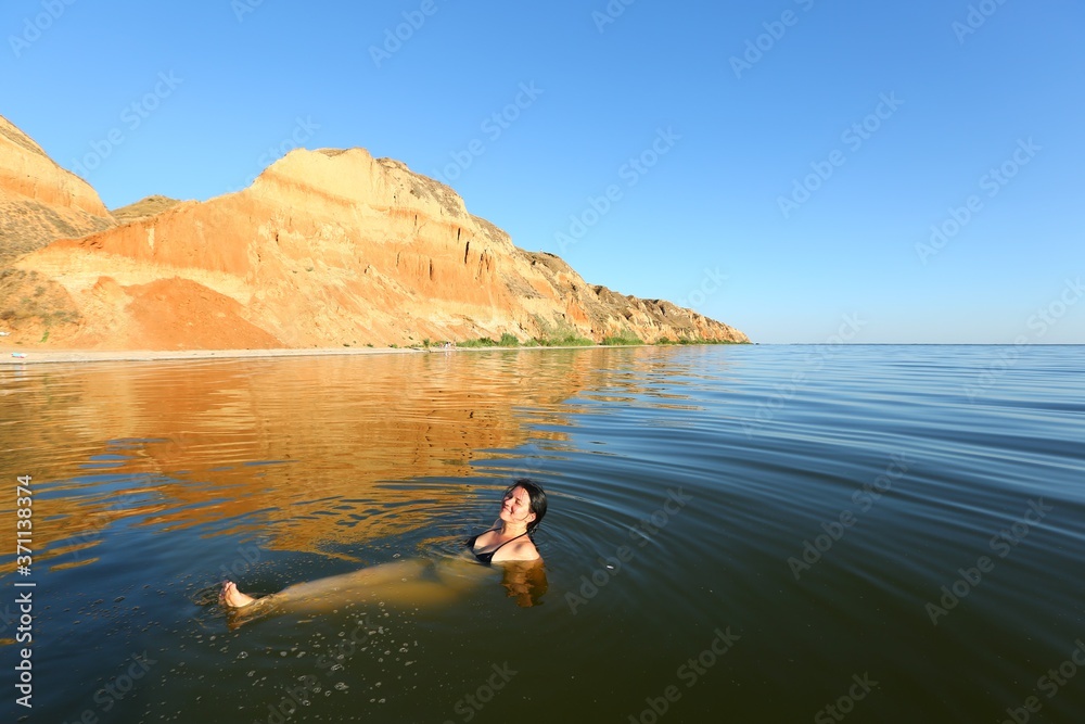 Young caucasian woman swimming in the Black sea at picturesque sunset landscape of Stanislav mountains, Ukraine