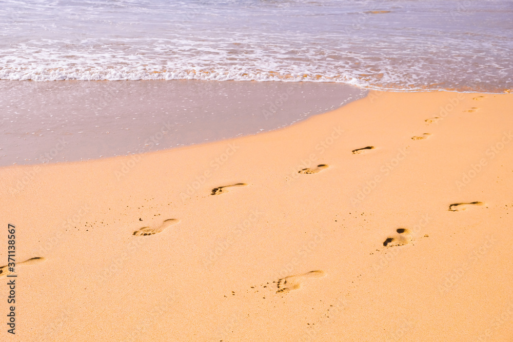Human footprints leading away from the viewer into the sea. Empty beach, tourism concept, travelling. Human footprints leading away from the viewer into the sea. Empty beach, tourism concept, travelling.