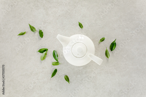 Herbal tea in a white teapot, with green tea leaves. Flat lay, top view. Tea concept