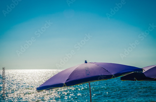 Beach umbrella by the sea. Sunset on the beach. A colorful  large awning to protect from the sun s rays. Summer. Day. Georgia. Black Sea.