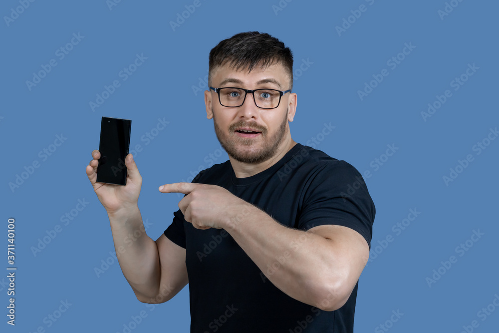 A man with glasses points to a cell phone. A person and a cellular connection. A man with glasses points to a cell phone. A person and a cellular connection.