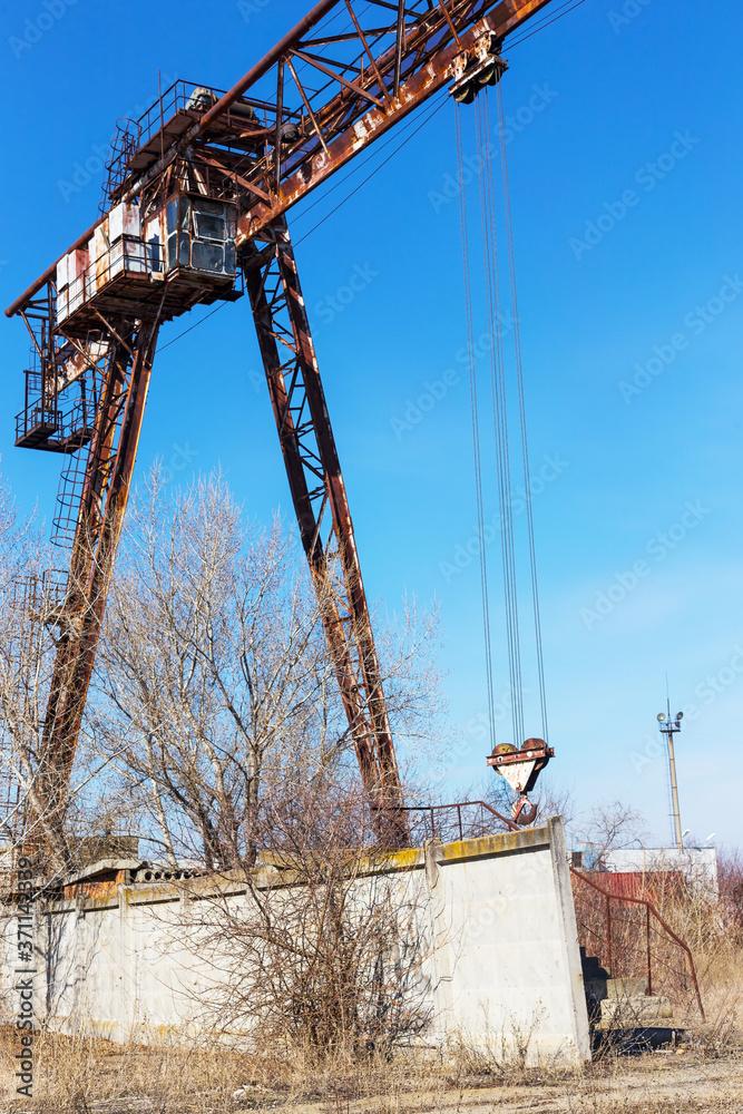 Old, rusty gantry crane on railroad, an abandoned concrete plant. Crisis, collapse of economy, and shutdown of production capacities have led to collapse. Global catastrophe. 