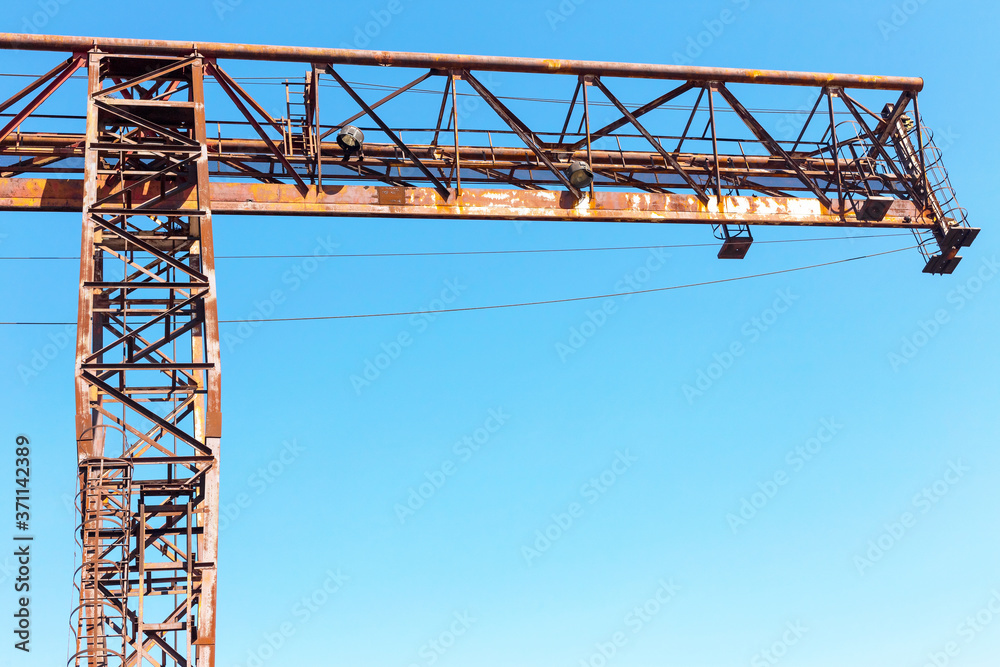 Old, rusty gantry crane on railroad, an abandoned concrete plant. Crisis, collapse of economy, and shutdown of production capacities have led to collapse. Global catastrophe. 