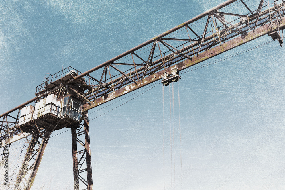 Old, rusty gantry crane on railroad, an abandoned concrete plant. Crisis, collapse of economy, and shutdown of production capacities have led to collapse. Effect of an old vintage photo.