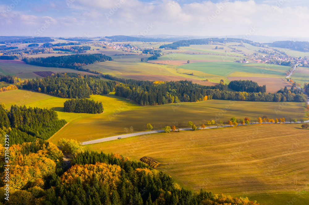Aerial autumn rural landscape with winding road, fields and forest