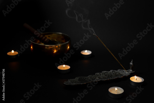 candles, a singing bowl, incense sticks on a black background. religious atmosphere