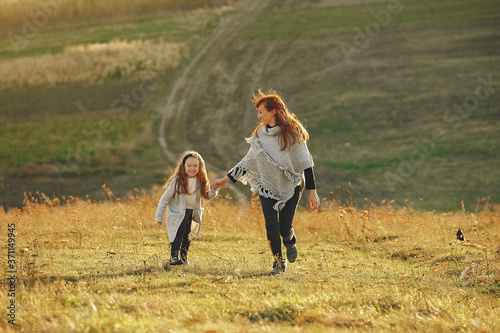 Family in a autumn field. Mother with red hair. Cute little girl