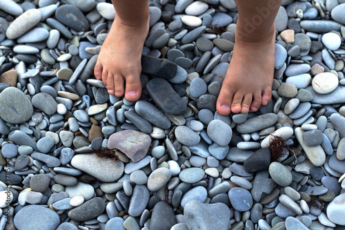Baby's feet on beautiful beach rocks. Source of pebbles. Concept of postcards and holidays with children. Family tourism on the Black sea. Copy space