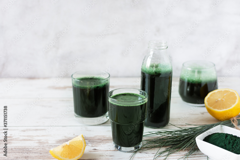 Fototapeta premium Spirulina drink with lemon and spirulina algae powder on white wooden table.