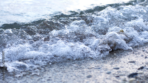 Sea wave on the sand. Sea foam from the wave. Blue transparent wave. Concept of postcards and tourist holidays. Copy space