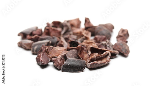 Chopped up cocoa pieces pile, isolated on white background, closeup