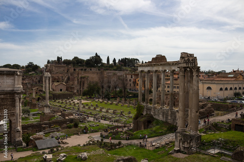 Roman forum in the sun against a dark, clouded sky. Ancient architecture and cityscape of historical Rome.